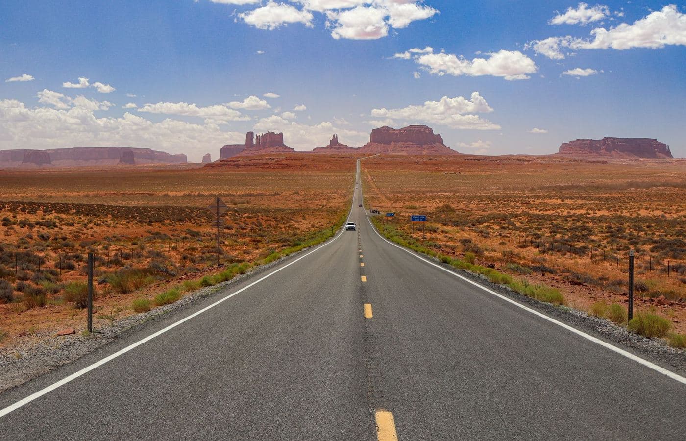 An open desert highway running toward Monument Valley